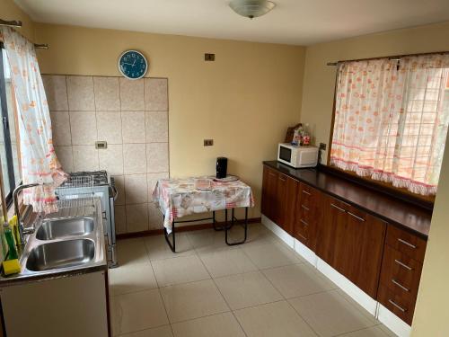 a kitchen with a sink and a table and a microwave at Casa Rukalma Estación in Villarrica