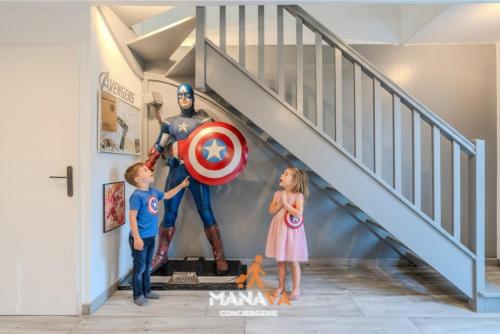 Una familia de pie junto a una estatua de un superhéroe en un pasillo en The Avengers House, en Magny-le-Hongre
