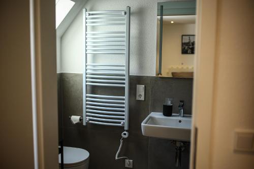 a bathroom with a sink and a toilet and a mirror at Lumé26 in Koblenz