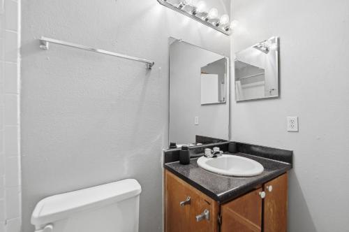 Un baño con lavabo, inodoro y espejo. en District West Apartments Simple Comfort & Value, en Doud