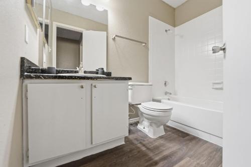 een witte badkamer met een toilet en een wastafel bij District West Apartments Comfort Made Simple in Doud