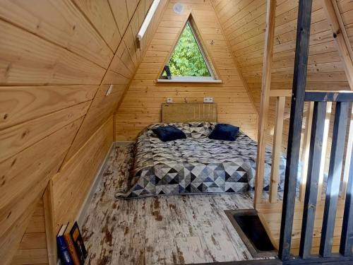 a bed in a wooden cabin with a window at М'юзіка Карпат in Yavoriv