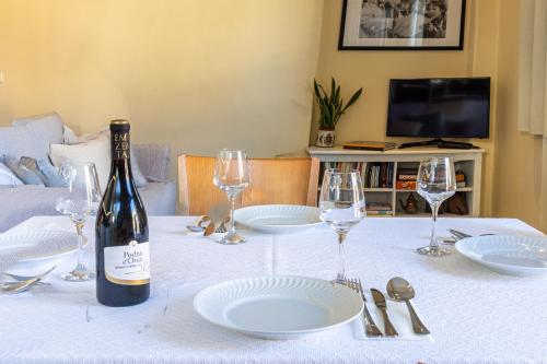 a bottle of wine sitting on a table with plates and glasses at Gouveia Forest Guest House in Gouveia