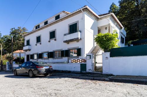 een auto geparkeerd voor een wit huis bij Gouveia Forest Guest House in Gouveia