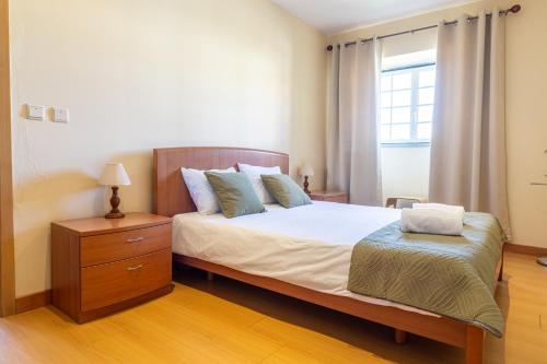 een slaapkamer met een bed, een ladekast en een raam bij Gouveia Forest Guest House in Gouveia