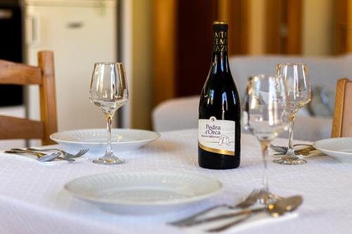 a bottle of wine sitting on a table with glasses at Gouveia Forest Guest House in Gouveia