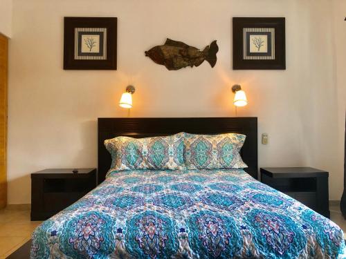 a bedroom with a bed with two night stands and a fish on the wall at Cadaques Bayahibe Family Apts in Bayahibe