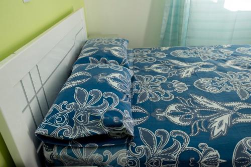 a bed with a blue and white comforter and pillows at Quarto com Vista para o Vale in Ribeira Grande