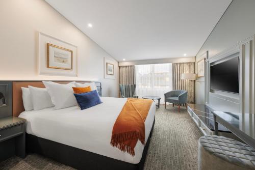 a hotel room with a large bed and a television at Millennium Hotel Queenstown in Queenstown