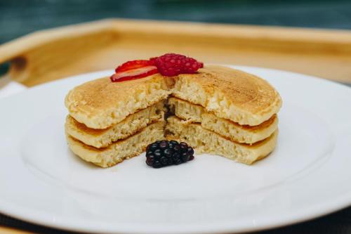 una pila de panqueques con bayas en un plato blanco en Holiday Inn & Suites - Mexico Felipe Angeles Airport by IHG, en Zumpango de Ocampo