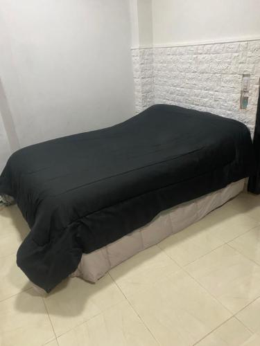 a bed with a black comforter in a room at Departamento para 2 personas in Buenos Aires