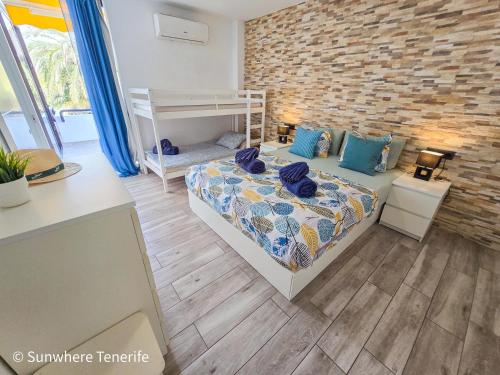 Un dormitorio con una cama y una pared de ladrillo. en Sunwhere Colon II apartment - Playa De Las Américas, en Arona