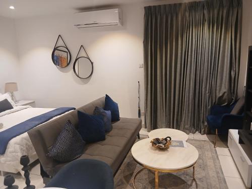 ein Wohnzimmer mit einer Couch, einem Bett und einem Tisch in der Unterkunft Embassy Gardens- Frank Homes in Accra