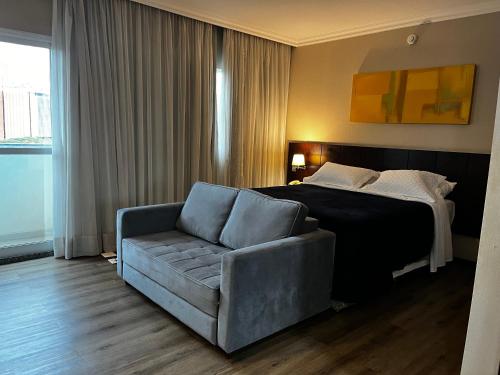 a hotel room with a bed and a couch at Quarto de hotel na Rua Verbo Divino in Sao Paulo