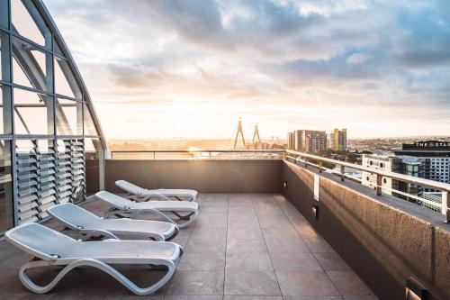 a group of lounge chairs on the roof of a building at Luxury bay view Darling Harbour Free Parking in Sydney
