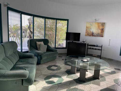 a living room with two chairs and a glass table at Villa Los Ojos in Charco del Palo