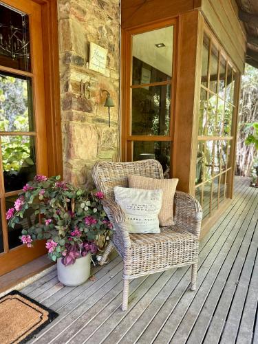 a wicker chair sitting on a porch with flowers at Stonehenge Retreat in Ballarat