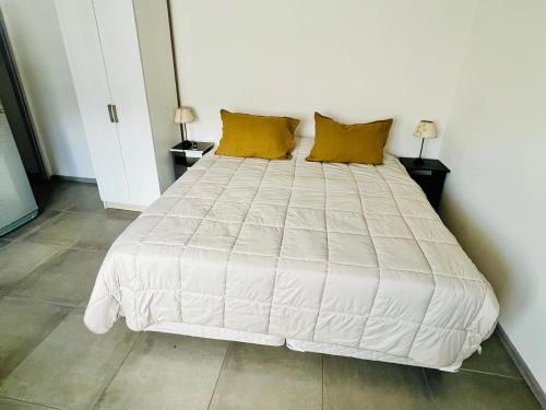 a white bed with yellow pillows in a bedroom at Departamentos Lucinda II in Ushuaia