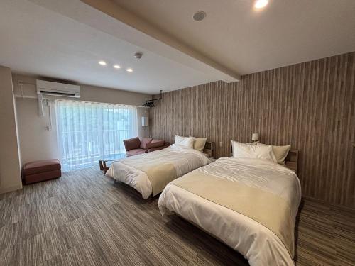 a hotel room with two beds and a couch at プリンスプラージュ沖縄301 in Onna