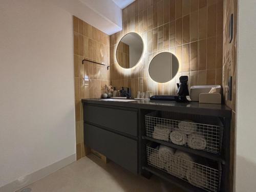 a bathroom with a sink and two mirrors at プリンスプラージュ沖縄301 in Onna