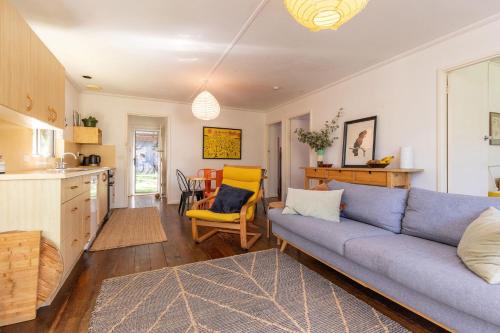 a living room with a blue couch and a kitchen at Pippis a Classic Beach House in Seal Rocks