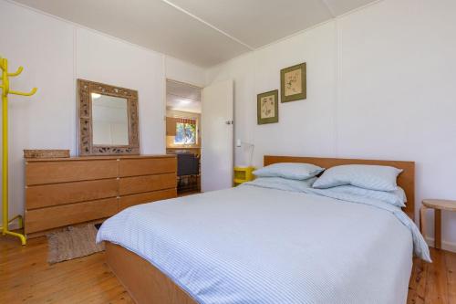 a bedroom with a bed and a dresser and a mirror at Pippis a Classic Beach House in Seal Rocks