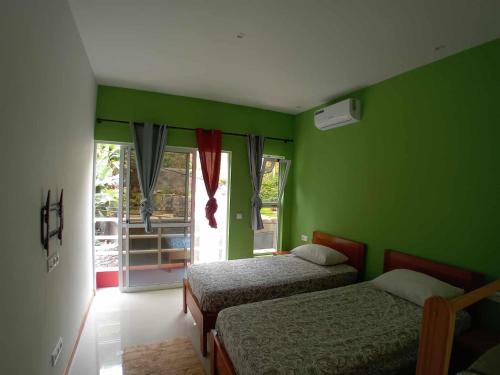 a green room with two beds and a window at Residencial Chez Flávia in Pombas