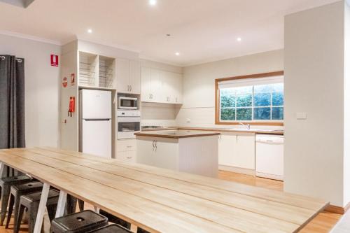 a kitchen with white cabinets and a wooden table at NRMA Ballarat Holiday Park in Ballarat