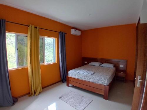 ein Schlafzimmer mit orangefarbenen Wänden, einem Bett und Fenstern in der Unterkunft Residencial Chez Flávia in Pombas