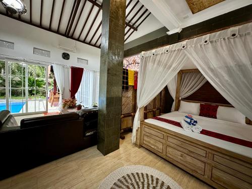 a bedroom with a canopy bed and a bathroom at Mangir Homestay in Banyuwangi