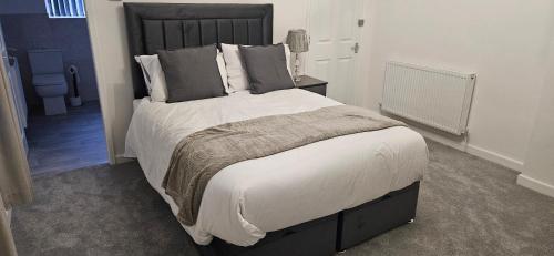 a bedroom with a large bed with white sheets and pillows at Rehoboth Stays in Dukinfield