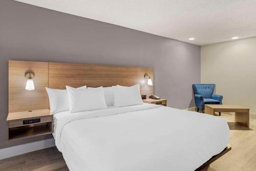 a bedroom with a large white bed and a blue chair at The Angler Hotel Livingston, an Ascend Collection Hotel in Livingston
