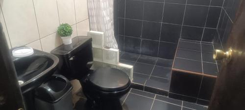 a bathroom with a black toilet and a sink at Cozy Rural House in Apata - Jauja 