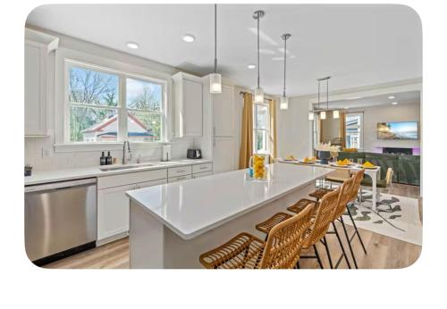 a kitchen with a large white counter top and chairs at Brand New 3 Bed 3 Bath Modern Home in Downtown in Raleigh