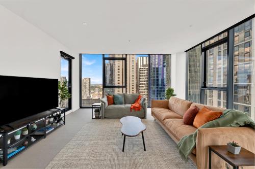 a living room with a couch and a flat screen tv at Zen Grand 3 Bedroom Residences 120m2 with up to 7 Separate Beds in Melbourne