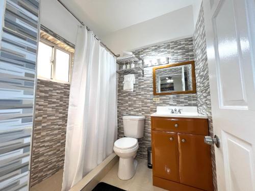 a bathroom with a toilet and a sink and a mirror at Luxury GuestHouse Suites in Cap-Haïtien