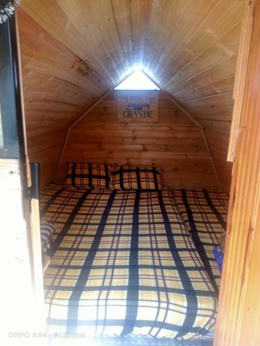 a bed in a wooden cabin with a light at Bahareque hospedaje in Monguí