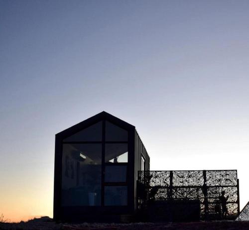 a black house with a window in the sunset at Luxury Tiny House with Private Hot Tub Access at the Grand Canyon in Valle
