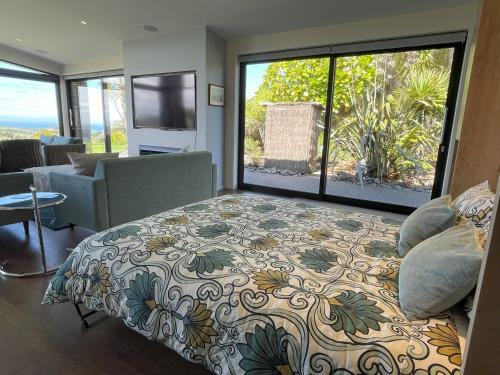 een slaapkamer met een bed en een groot raam bij Matapouri & Tutukaka Spectacular Coastal Views- Aroha Luxury Guest Suite in Tutukaka