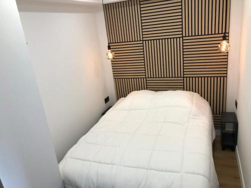 a bedroom with a white bed and a wooden wall at Studio vue sur la mer in Neufchâtel-Hardelot