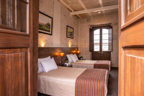 Una habitación de hotel con dos camas y una ventana. en Acolpacha Tambo Boutique, en Arequipa