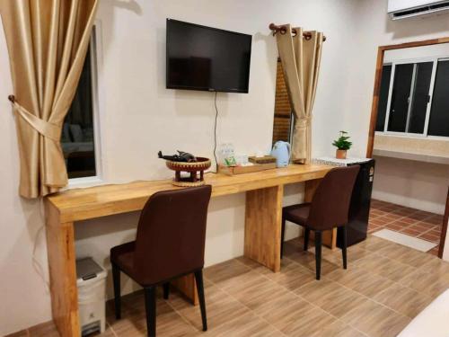 a wooden table with chairs and a television on a wall at Pai Pavilion in Pai