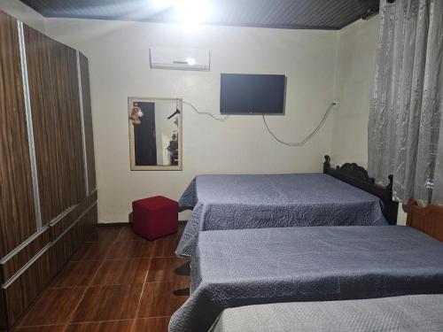 Una habitación con dos camas y un televisor de pantalla plana. en morada da felicidade, en São Gabriel