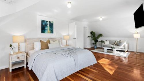 a white bedroom with a bed and a tv at 2 Marma Retreat - Peaceful Surrounds with Heated Pool & Spa in Red Hill