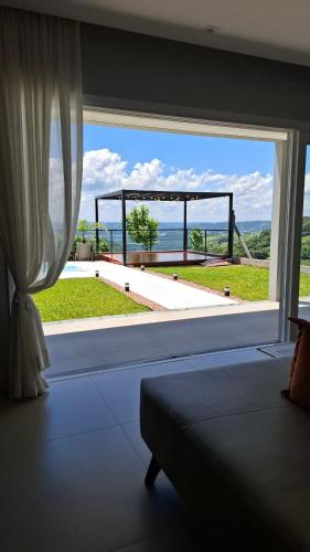 a bedroom with a large window with a view of the ocean at Casa 2 suítes, ofurô, piscina no Vale dos Vinhedos in Monte Belo