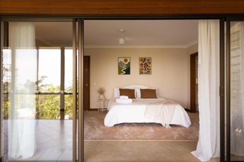 a bedroom with a bed and sliding glass doors at Tranquil mountain escape with bushland views in Mount Tamborine