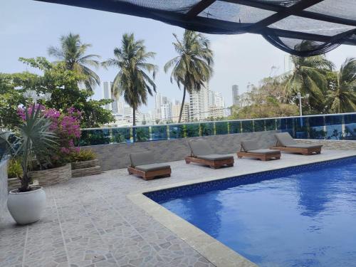 a swimming pool with lounge chairs and palm trees at Apartamento cerca Bocagrande in Cartagena de Indias
