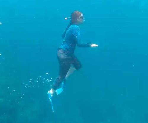 a woman is standing on a surfboard in the water at Majagua in Bahía Solano