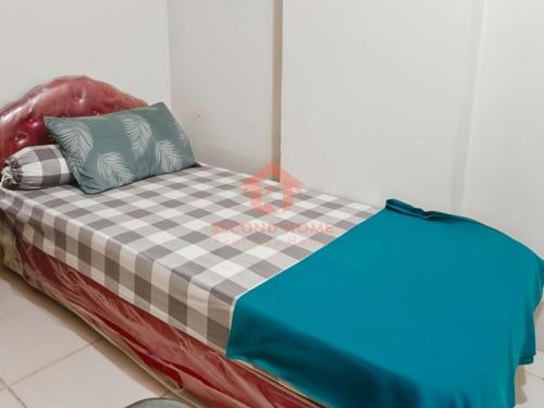1 cama con manta a cuadros y almohadas en Cozy 2BR Pinewood Apt Jatinagor Pool, en Cilimus 2