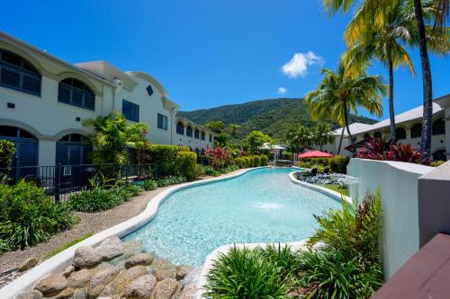 a swimming pool in front of a building with a resort at Mango Lagoon Resort & Wellness Spa in Palm Cove